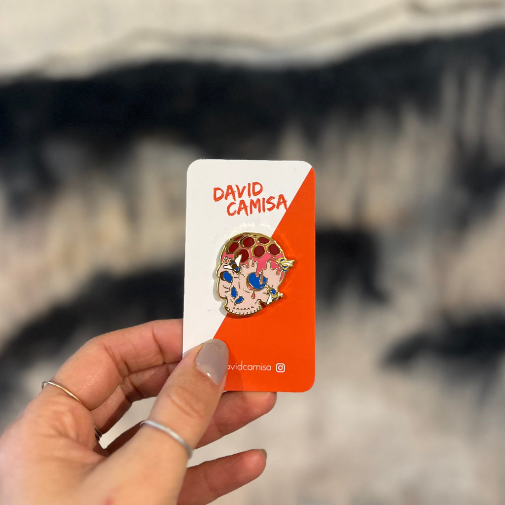 Hand holding a card with a colorful brooch design against a blurred background